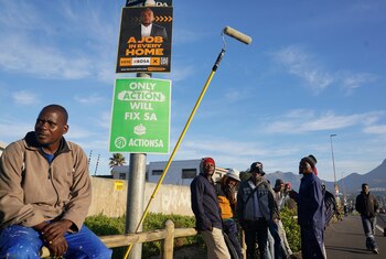 Desempleados esperan alguna oferta para un trabajo diario informal junto a carteles con publicidades electoral en Ciudad del Cabo REUTERS/Nic Bothma