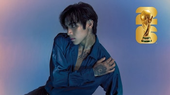 Hombre joven de cabello oscuro y tatuajes con camisa azul sedosa. Fondo degradado azul-violeta. Trofeo de la Copa Mundial FIFA 2026 visible en la esquina superior derecha.