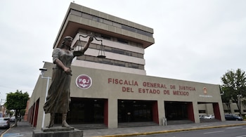 Vista exterior del edificio de la Fiscalía General de Justicia del Estado de México, con una estatua de la Dama de la Justicia en primer plano.