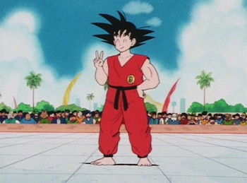 Imagen de anime de Son Goku, un joven con cabello negro puntiagudo y uniforme de artes marciales rojo, de pie y haciendo un signo de paz