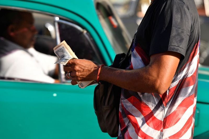Foto de archivo ilustrativa de un hombre con una remera con los colores de EEUU con un fajo de pesos cubanos en La Habana
February 10, 2025. REUTERS/Norlys Perez