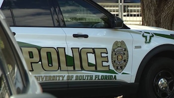 Primer plano del lateral de un SUV policial blanco y verde de la Universidad del Sur de Florida con el texto 'POLICE' y un escudo