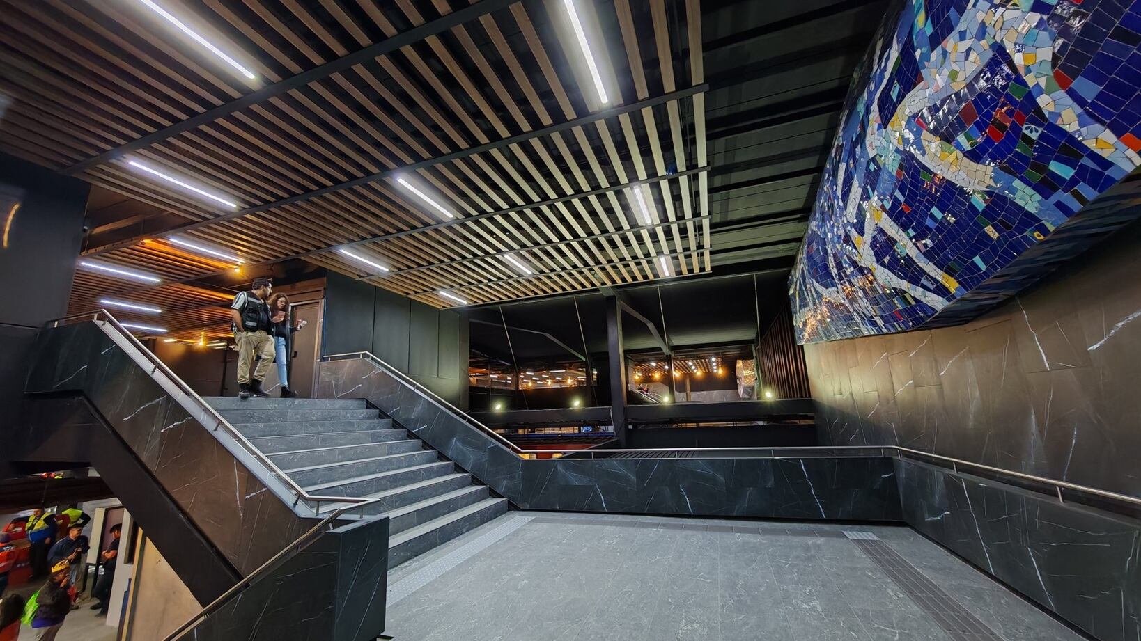 El interior de la terminal Tasqueña de la Línea 2 del Metro CDMX luce modernizado con nuevas escaleras, iluminación y un mural de mosaicos coloridos como parte de su remodelación. (X/ @caminalex)