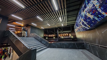 Interior modernizado de la terminal Tasqueña: escaleras de mármol oscuro, techo de lamas de madera, luces LED y un gran mural de mosaicos coloridos