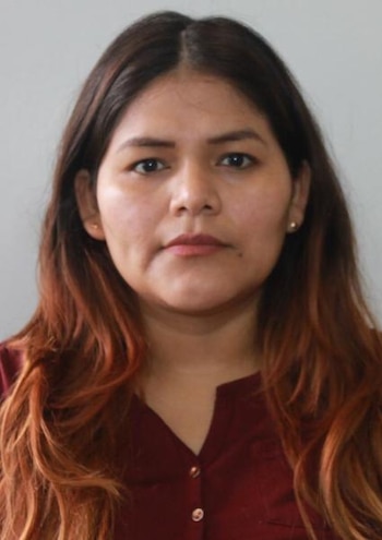 Retrato frontal de una mujer de cabello largo castaño rojizo y blusa guinda frente a un fondo claro