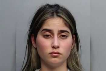Retrato de una mujer joven con cabello oscuro y mechas claras, mirando al frente, sobre un fondo gris liso