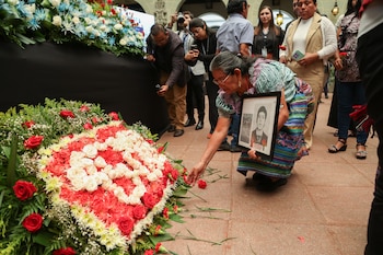 FOTODELDÍA AME2449. CIUDAD DE GUATEMALA (GUATEMALA), 19/06/2026.- Una familiar de desaparecidos pone una flor en un altar durante un acto conmemorativo este viernes, en Ciudad de Guatemala (Guatemala). En el marco del día Nacional contra la Desaparición Forzada en Guatemala, que se conmemora cada 21 de junio, se realizó el lanzamiento del mecanismo de búsqueda humanitaria de personas desaparecidas durante el conflicto armado interno en Guatemala 2026-2036, en el Palacio Nacional de la Cultura en Ciudad de Guatemala. EFE/ Mariano Macz