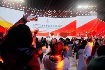 Olympics - Beijing 2022 Winter Olympics - Torch Relay - Beijing, China - February 2, 2022. Spectators wave flags and cheer during a performance at the end of the torch relay session at the Shougang Park. REUTERS/Florence Lo