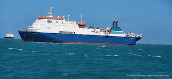 Dos barcos en el mar. El buque principal, blanco y azul, lleva el nombre 'Wave Sentinel'. Un segundo barco, azul y blanco, se observa al fondo
