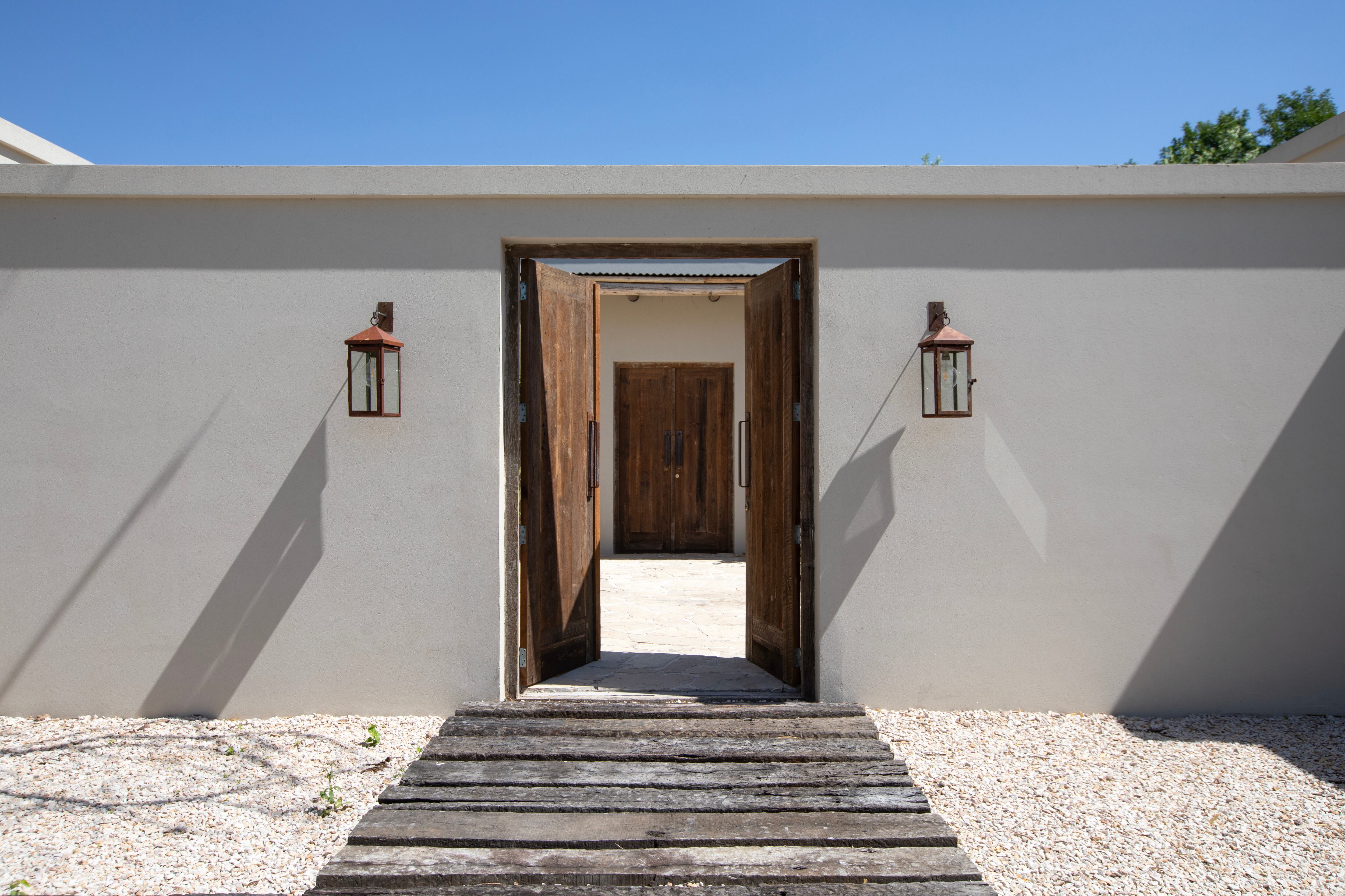 El diseño exterior se apoya en la coherencia de materiales y formas. La puerta de acceso, fabricada en Pino Brasil rústico con manijones hechos a medida por un herrero, marca el tono desde la entrada