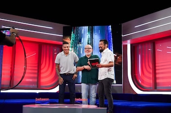 Tres hombres sonrientes en un set de televisión iluminado. De izquierda a derecha: Paolo Guerrero, un hombre con lentes y un hombre con barba sosteniendo una carpeta