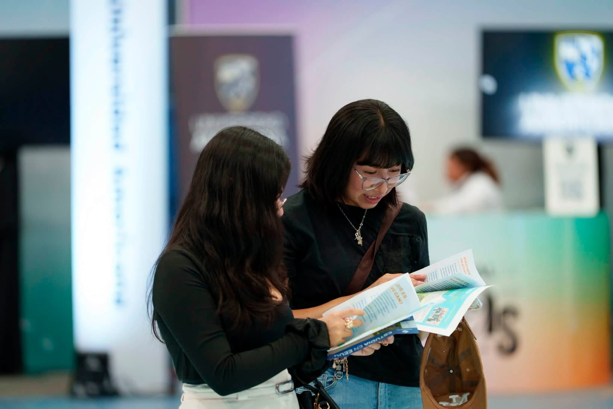 Dos jóvenes revisan folletos con programas académicos para estudiar en Estados Unidos durante un evento educativo. (Segeplan Guatemala)