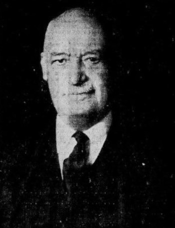 Retrato en blanco y negro de un hombre con calvicie. Viste traje oscuro y corbata. La imagen muestra una textura granulada