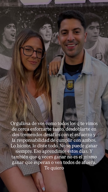 Una mujer con anteojos y un hombre posan sonrientes frente a un mural con imágenes de Diego Maradona. La imagen contiene texto sobreimpreso