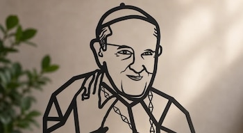 Silueta recortada en líneas negras con el rostro y la mano levantada del papa Francisco, situada delante de una pared clara y una planta