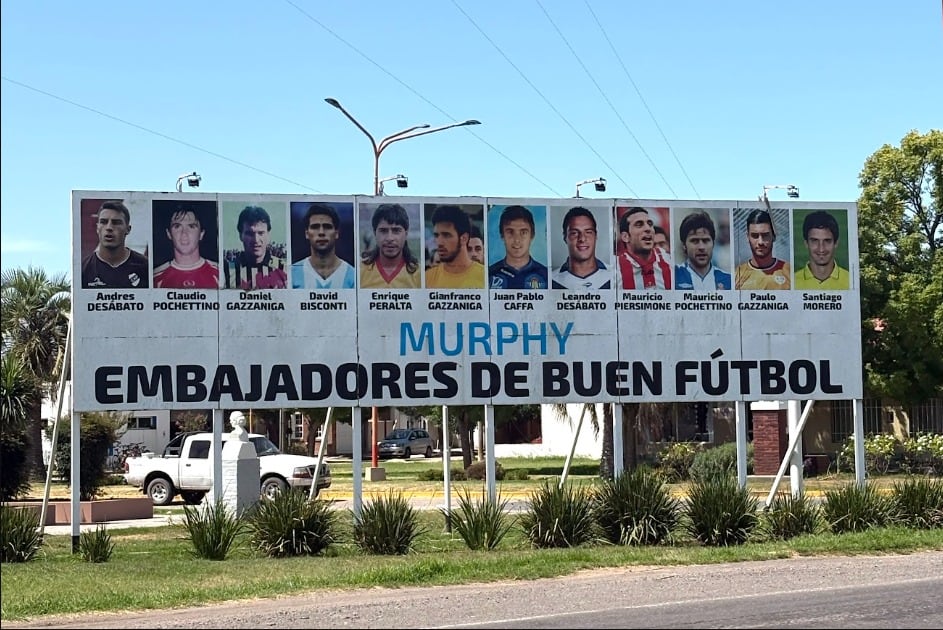Una valla publicitaria a lo largo de la ruta principal que lleva a Murphy muestra las caras de 12 “embajadores del buen fútbol”: hijos predilectos de la zona que pasaron de jugar en un campo improvisado a las ligas profesionales (Teo Armus/The Washington Post)