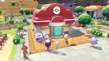 Vista aérea de un vibrante pueblo de videojuego con un gran Centro Pokémon rojo en el centro, rodeado de personajes, arbustos, árboles y edificios coloridos