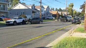 Vehículos con daños en el frente permanecen en una calle residencial acordonada con cinta amarilla de la policía