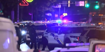 Múltiples patrullas policiales con luces rojas y azules encendidas ocupan una calle nocturna junto a agentes armados