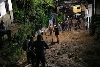 Members of the community work to clean up an area where a river of mud overflowed after heavy rains, in Sabaneta, Colombia, May 8, 2025. REUTERS/Juan David Duque