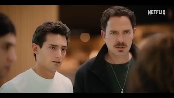 Un hombre con bigote y un hombre joven, ambos con cabello oscuro, miran al frente. El logo de Netflix aparece en la esquina superior derecha