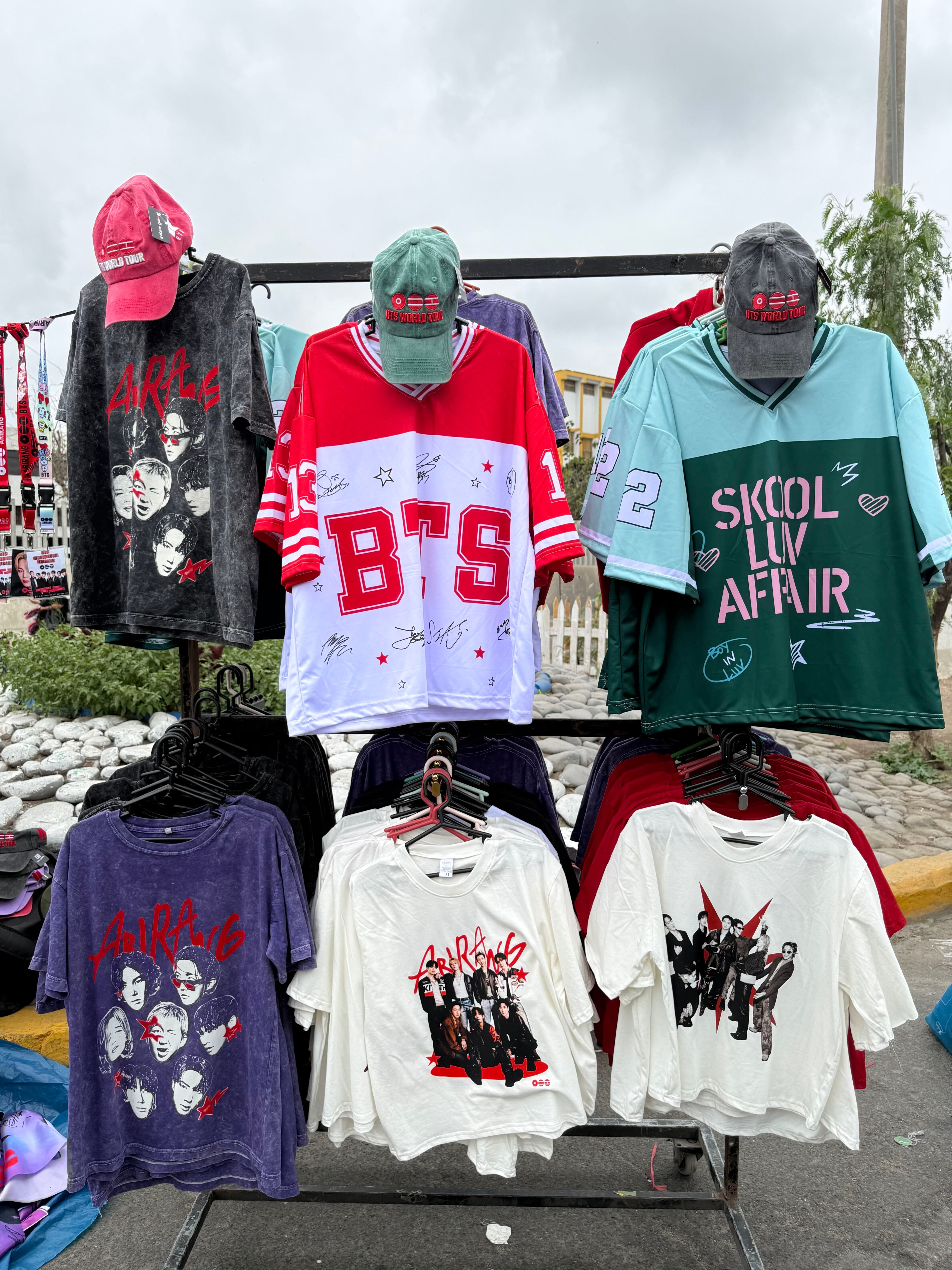 Vendedores ambulantes ofrecen camisetas y gorras del grupo surcoreano BTS en los exteriores del Estadio San Marcos de Lima. (Paula Díaz)