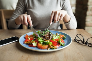 Una mujer comiendo un plato variado y equilibrado (Magnific)