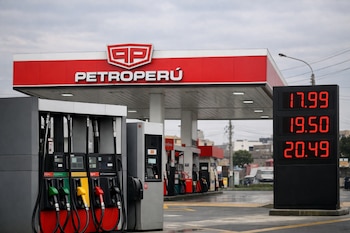 Vista frontal de una estación de servicio Petroperú con surtidores de combustible y un cartel electrónico que muestra precios altos en soles, bajo un cielo nublado.