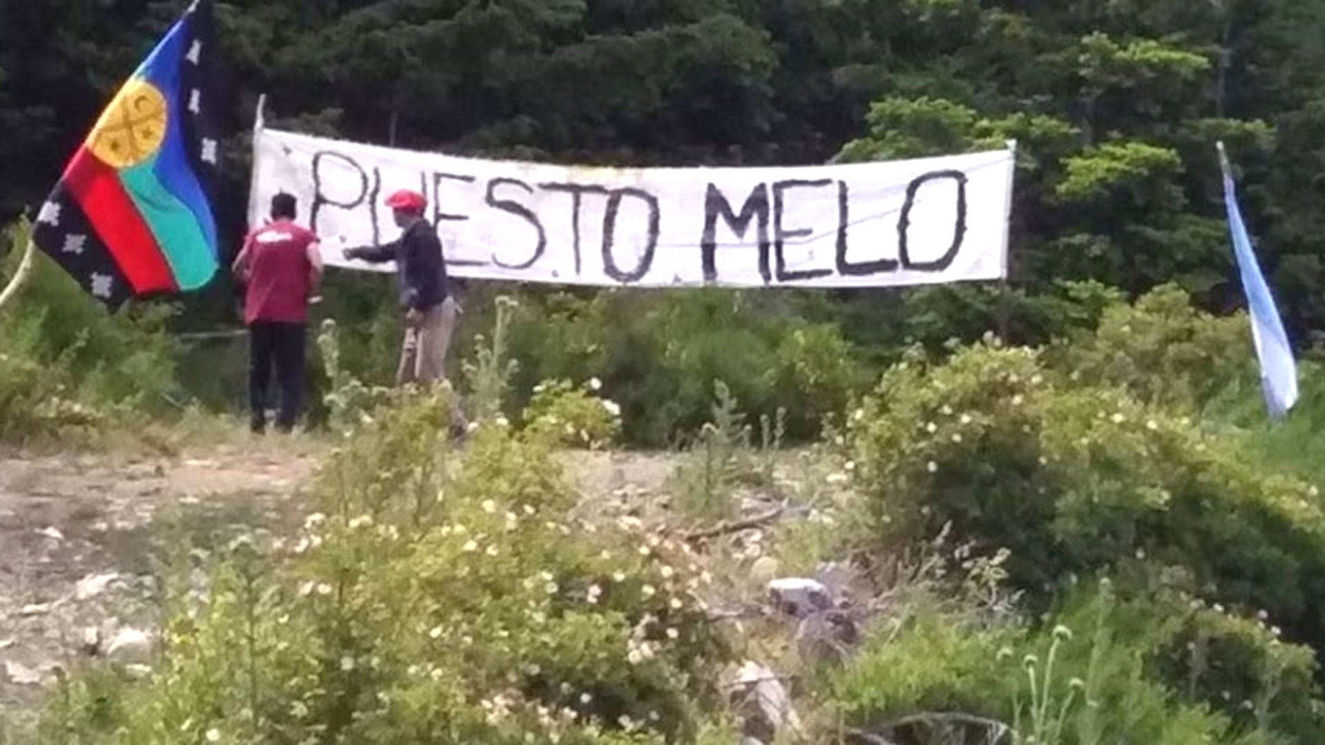 Miembros de la comunidad Mapuche protestan con sus banderas y un cartel de