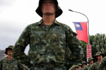 Una bandera de Taiwán ondea mientras soldados se preparan para celebrar el Día Nacional, que conmemora el 113° aniversario de la República de China, nombre oficial de la isla, en Taipéi (REUTERS/Ann Wang).