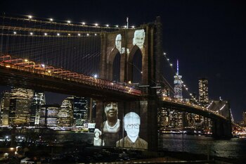 Rostros de víctimas del COVID-19 proyectados en el Puente de Brooklyn (Reuters)