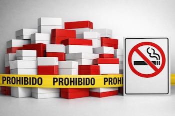 Pilas de cajas de cigarrillos blancas y rojas detrás de una cinta amarilla que dice 'Prohibido'. A la derecha, una señal blanca de no fumar con un cigarrillo tachado.