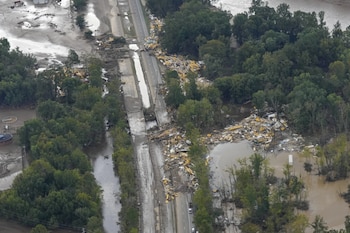 Vista aérea de una autopista gravemente dañada y zonas inundadas con abundante escombros arrastrados por el agua, rodeadas de árboles