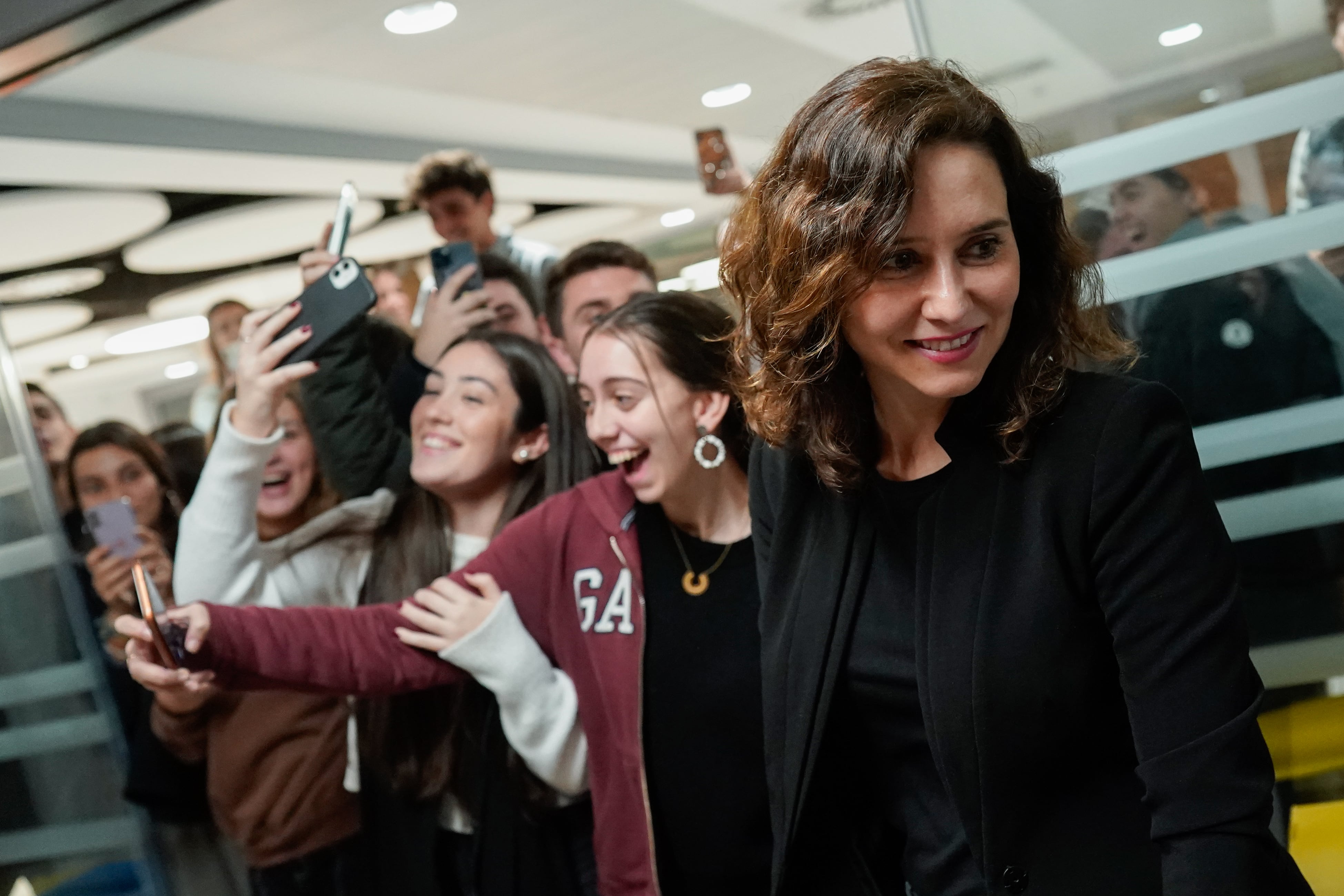 La presidenta de la Comunidad de Madrid, Isabel Díaz Ayuso, con un grupo de jóvenes