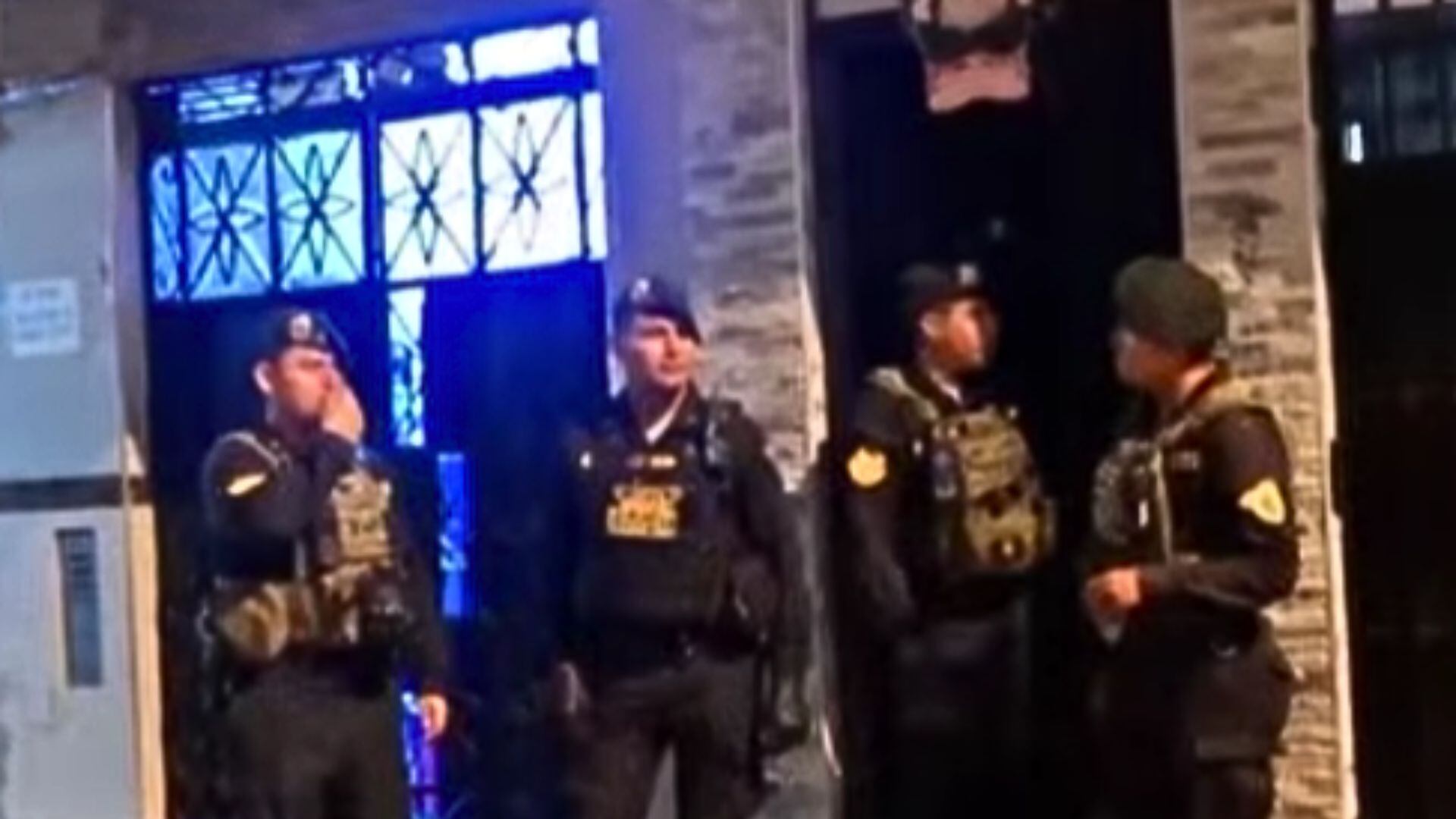 Cuatro hombres uniformados con equipo táctico se encuentran fuera de un edificio durante una operación nocturna. (Exitosa)
