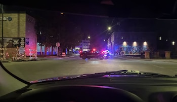 Vista desde el interior de un auto hacia una calle nocturna donde hay patrullas de policía con luces de emergencia encendidas