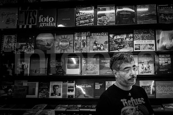 Hombre con gafas y barba frente a estanterías repletas de libros en blanco y negro