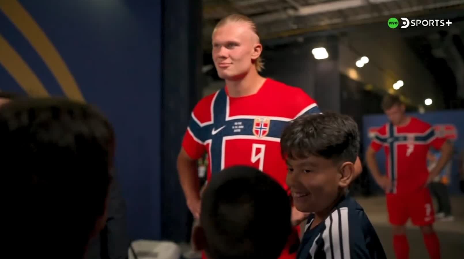 Erling Haaland sonríe amablemente mientras interactúa con un grupo de niños visiblemente emocionados que le piden una camiseta, previo a un encuentro de cara al Mundial 2026.