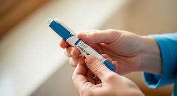 Manos de una persona adulta sosteniendo un dispositivo de inyección de semaglutida tipo pluma azul y blanco con etiqueta genérica, enfocado nítidamente.