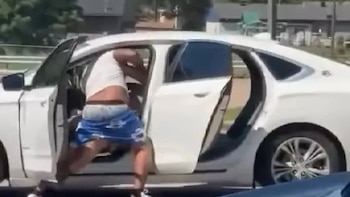 Un hombre con camiseta blanca y pantalones cortos azules es visto saliendo de la puerta del conductor de un Chevrolet Volt blanco con la puerta abierta