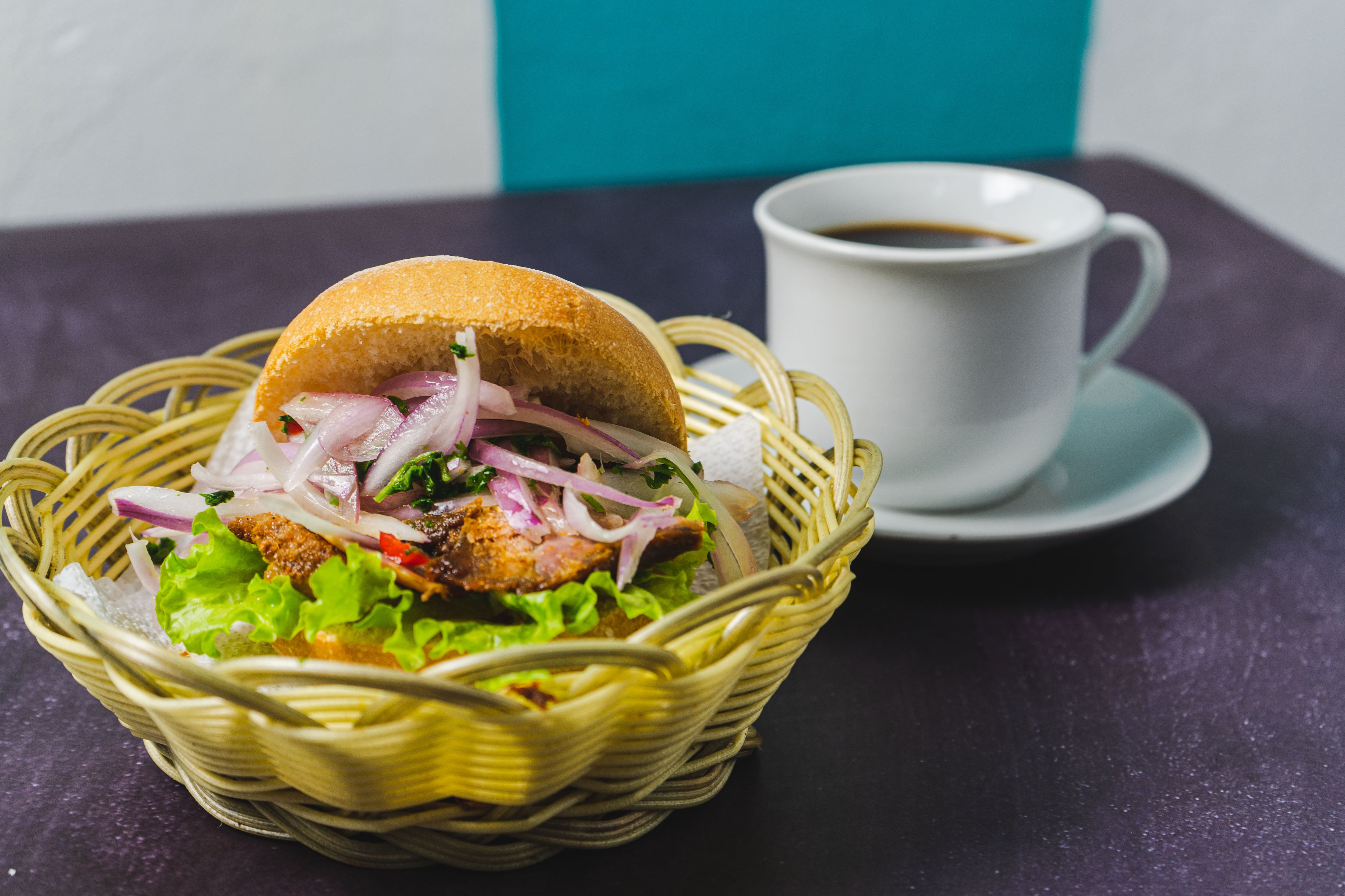 El pan con chicharrón de Perú lleva panceta de cerdo crocante, salsa criolla, batata y pan francés, es un clásico del desayuno limeño (Pexels)