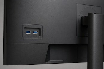 Parte trasera de un monitor negro con dos puertos USB horizontales con pestaña azul y el soporte sobre el lado derecho.