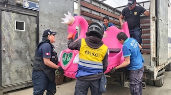 Varios trabajadores con chalecos amarillos y uniformes oscuros suben una estructura rosa con forma de cisne a un camión.