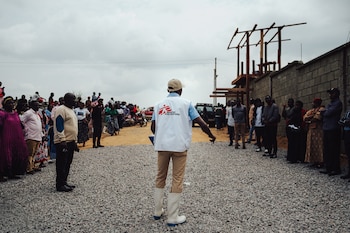 Toussaint, promotor de salud de MSF, se dirige a los familiares de un fallecido en el centro Elykia, en Bunia, para explicarles cómo se desarrolla la despedida. La organización dice que trabaja con las comunidades para disipar los rumores sobre lo que ocurre dentro de los centros de tratamiento (Foto: Julien Dewarichet/MSF, 22 de julio)