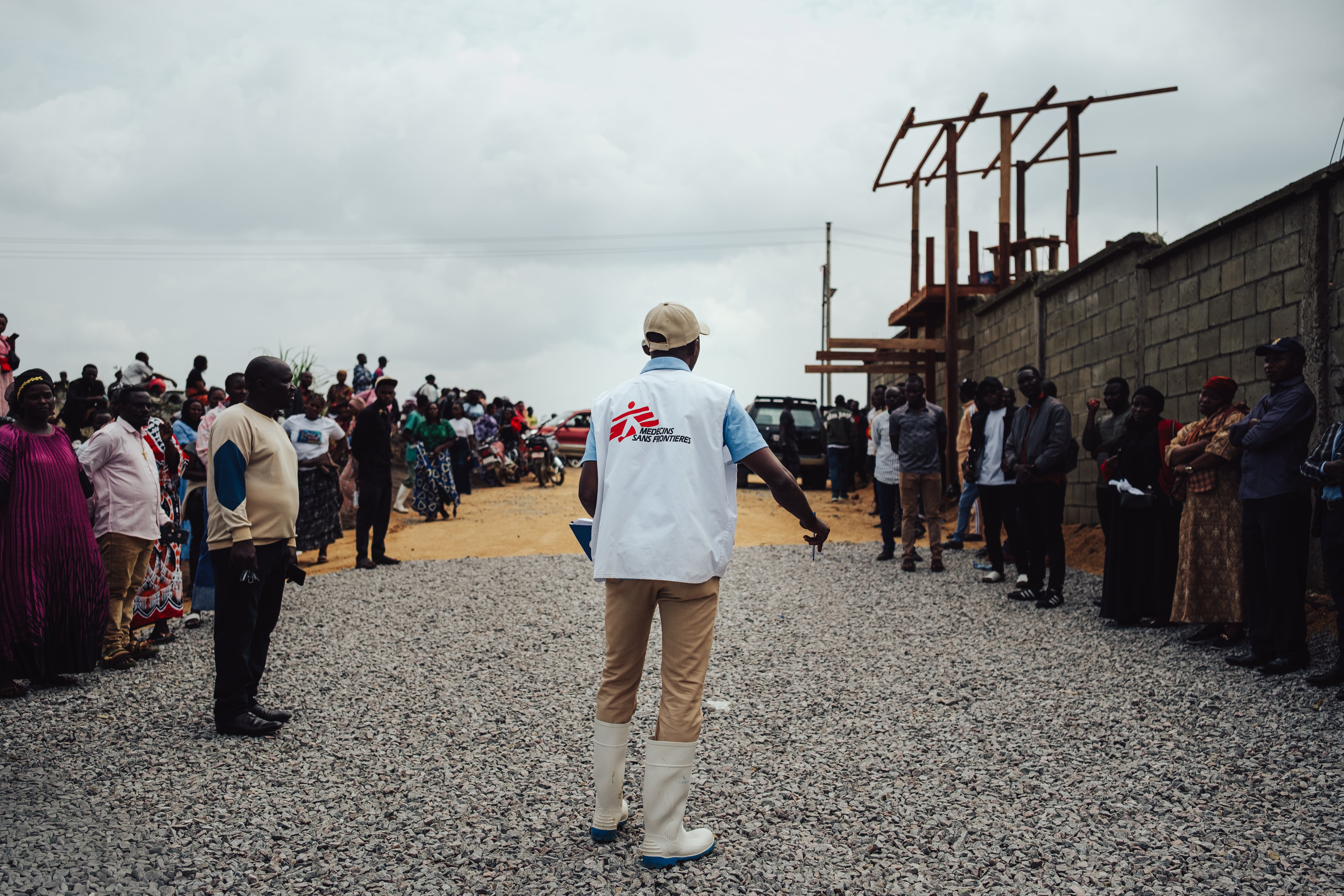 Toussaint, promotor de salud de MSF, se dirige a los familiares de un fallecido en el centro Elykia, en Bunia, para explicarles cómo se desarrolla la despedida. La organización dice que trabaja con las comunidades para disipar los rumores sobre lo que ocurre dentro de los centros de tratamiento (Foto: Julien Dewarichet/MSF, 22 de julio)