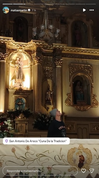 Matías Martín, con gorro gris y camiseta negra, mirando hacia arriba dentro de una iglesia con un altar dorado, estatuas religiosas y un candelabro