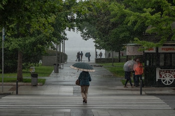 Varias personas se protegen de la lluvia en Santander, a 14 de mayo de 2026. (EFE/ Román G. Aguilera)