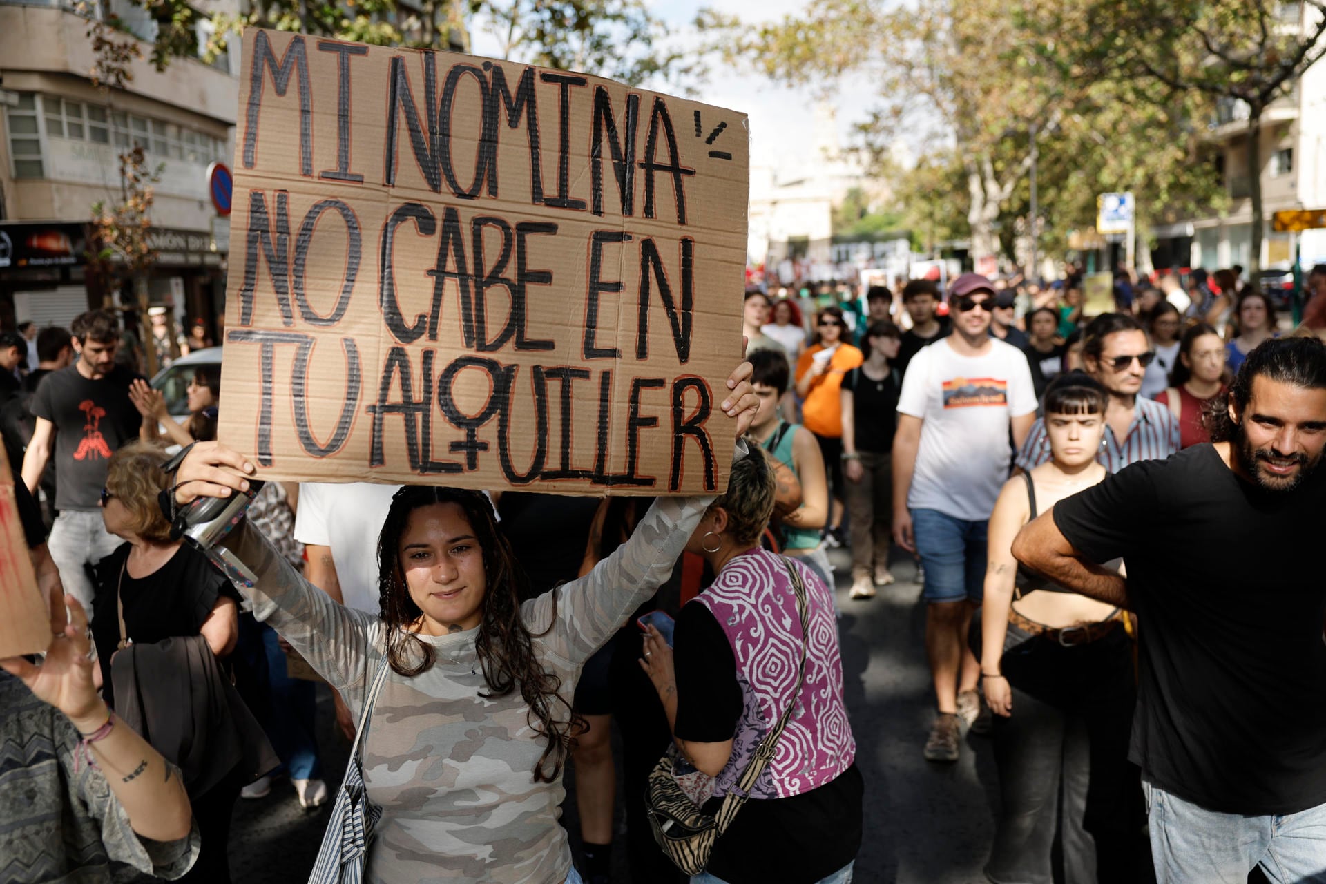 Una manifestante sostiene un cartel de cartón con la frase