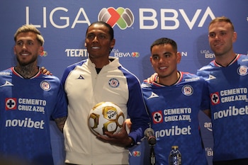 Cuatro hombres sonríen ante un fondo azul de Liga BBVA. Tres visten camisetas de Cruz Azul y uno una chaqueta. El hombre central sostiene un balón de fútbol