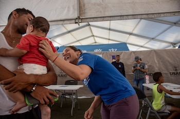 Tras los terremotos en Venezuela, una trabajadora de ACNUR saluda a un bebé que está junto a su padre en el Centro de Transición César Nieves, en La Guaira, Venezuela (Créditos ACNUR - Diana Diaz.)